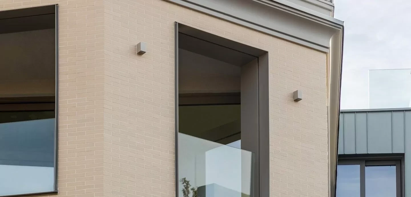 Nahansicht einer dunklen Fenstereinfassung an einer hellen Fassade — NOVOFRAME